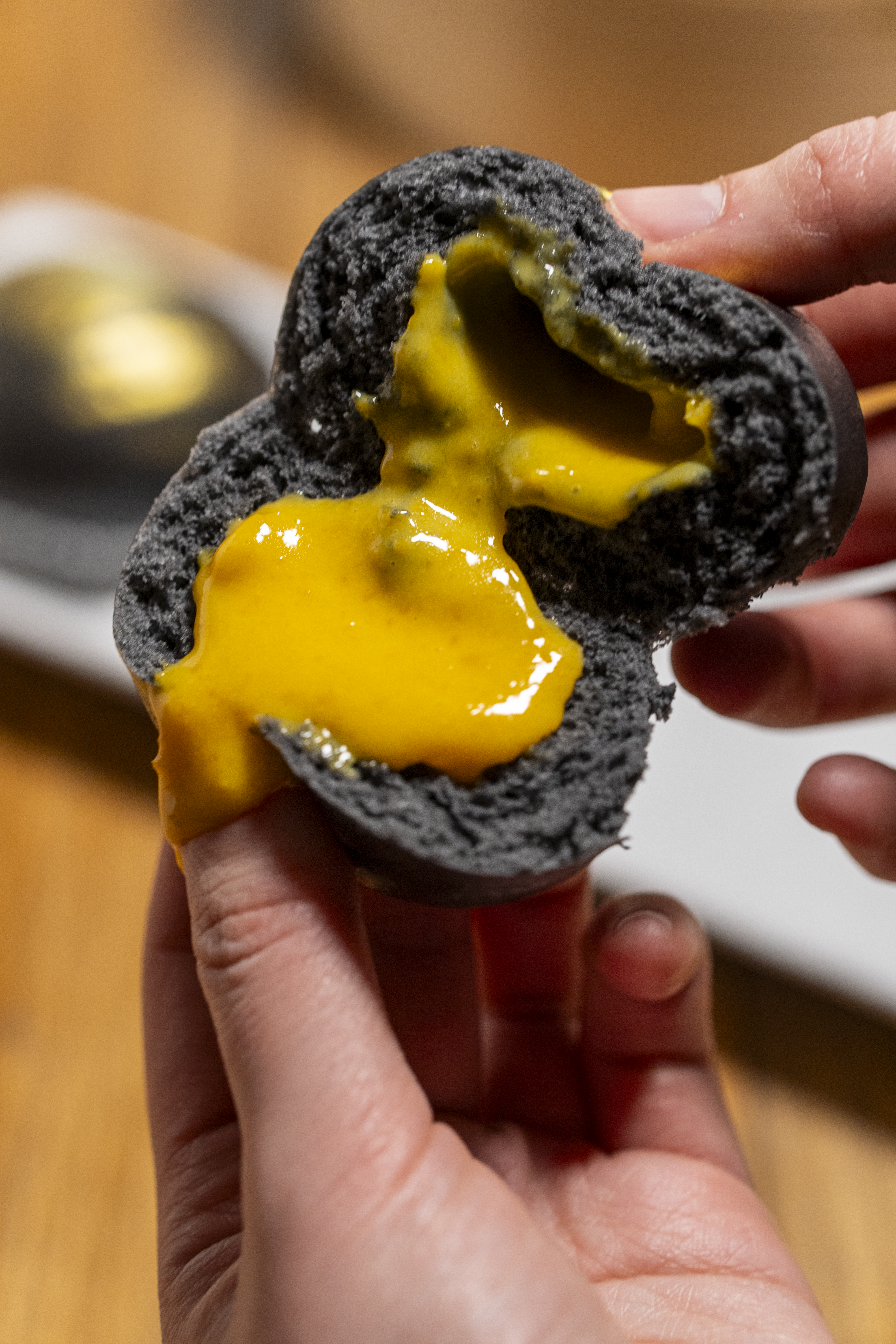 black gold lava bun broken open with custard